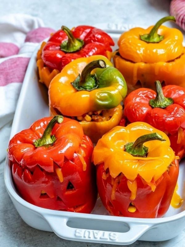 Bright orange mini peppers filled with seasoned rice, black beans, and melted cheese, topped with a black olive “eye.”
